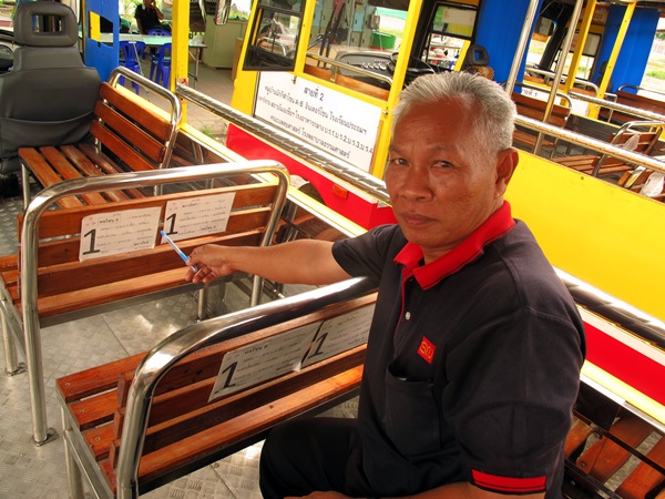 สมชาย นารี ชี้ป้ายหลังที่นั่งให้ดู